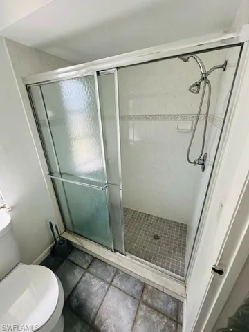 Bathroom featuring tile patterned floors, toilet, and an enclosed shower