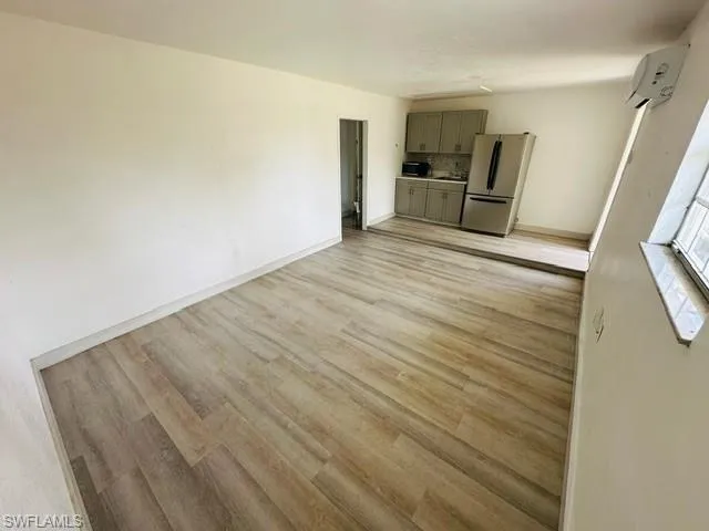 Unfurnished living room with a wall mounted air conditioner and light hardwood / wood-style flooring