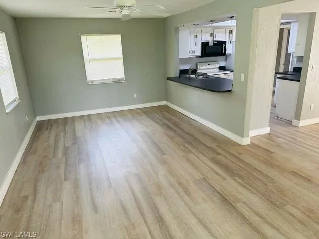 Kitchen with ceiling fan, light hardwood / wood-style floors, white cabinets, and a healthy amount of sunlight