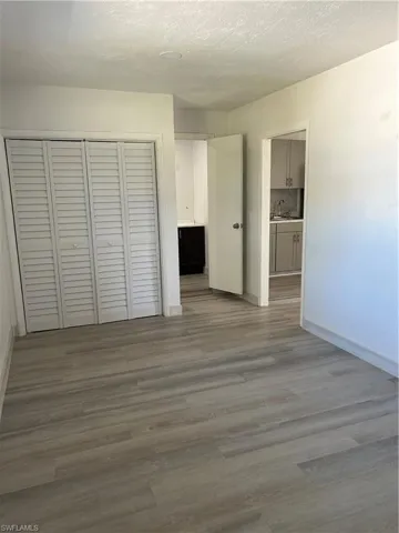Unfurnished bedroom with hardwood / wood-style floors, a closet, and a textured ceiling