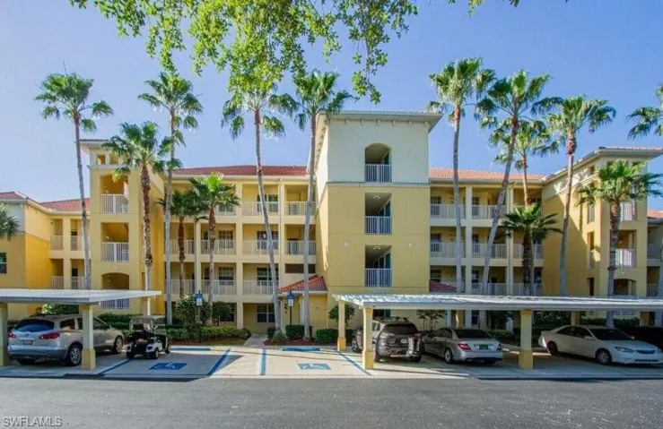 View of apartment building / complex featuring covered and uncovered parking