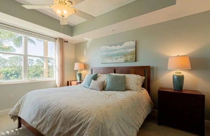 Carpeted bedroom with ceiling fan and baseboards