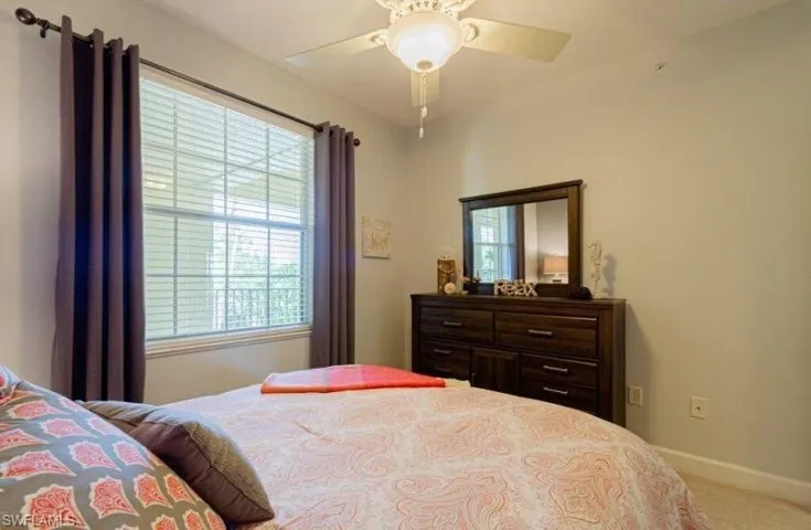 Carpeted bedroom featuring multiple windows and ceiling fan