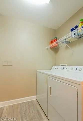 Laundry room with light wood-style floors and washing machine and clothes dryer