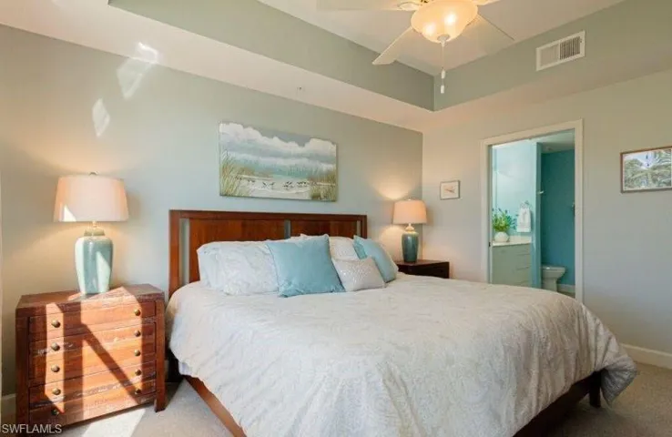 Bedroom with carpet, a ceiling fan, and ensuite bath
