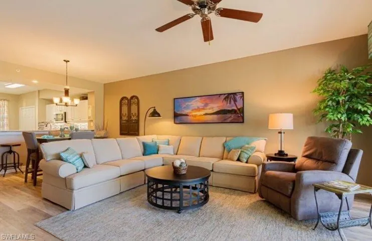 Living room featuring light wood finished floors, hanging lights, and ceiling fan