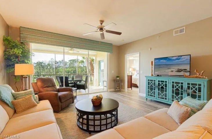 Living room with wood finished floors, a ceiling fan, and a sunroom
