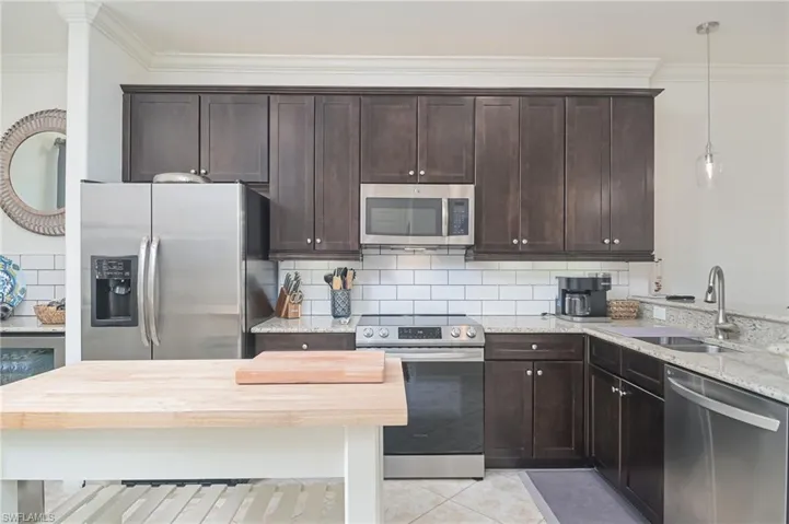 Kitchen featuring appliances with stainless steel finishes, pendant lighting, tasteful backsplash, and sink