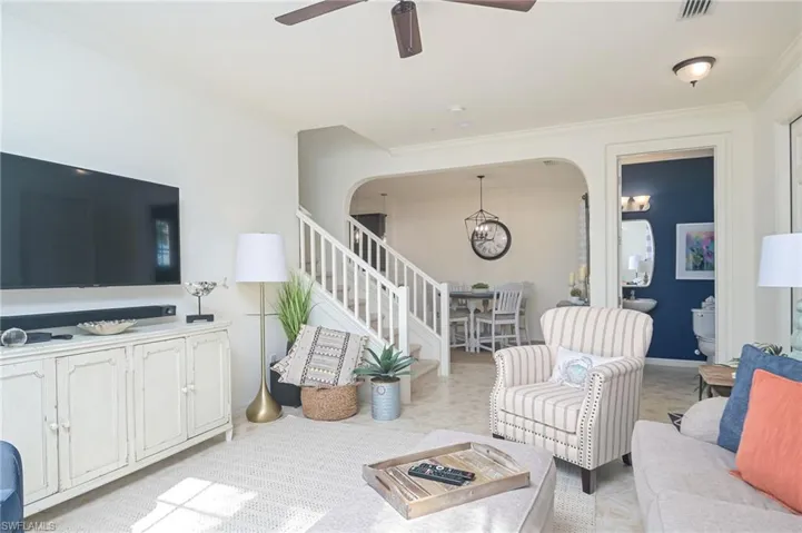 Carpeted living room with ornamental molding and ceiling fan