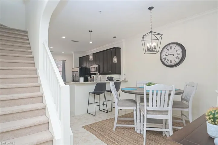 Dining space featuring a chandelier, sink, light tile patterned floors, and ornamental molding