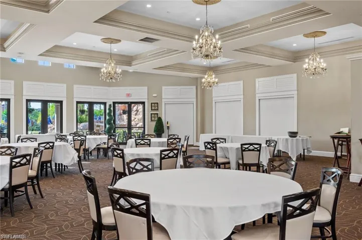 Carpeted dining space featuring ornamental molding, a notable chandelier, and coffered ceiling