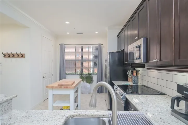 Kitchen featuring crown molding, stove, dark brown cabinetry, and tasteful backsplash