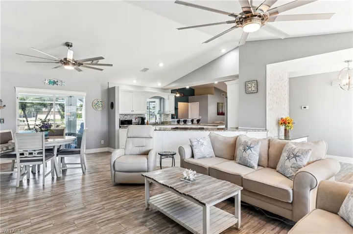 Living room featuring ceiling fan, lofted ceiling, and light hardwood / wood-style flooring