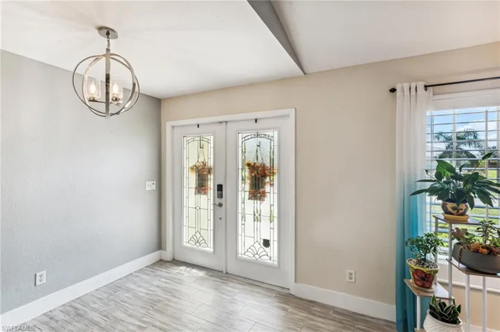 Foyer entrance featuring french doors, an inviting chandelier, and light wood-type flooring