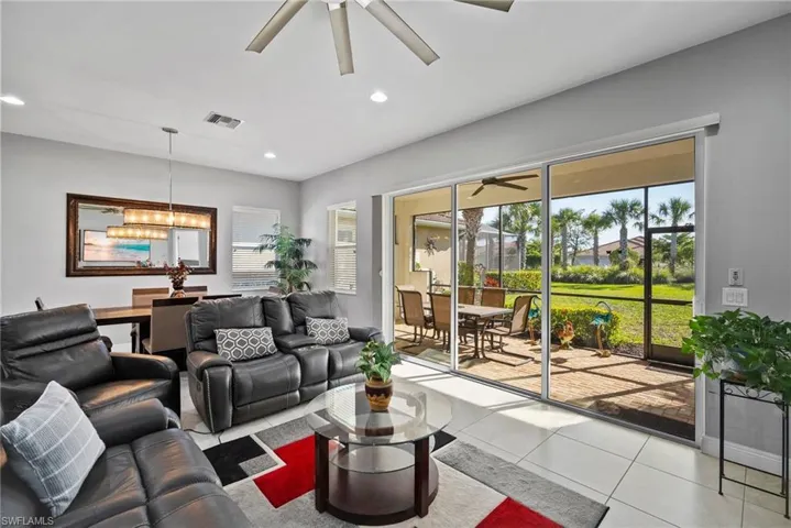 Tiled living room featuring ceiling fan with notable chandelier
