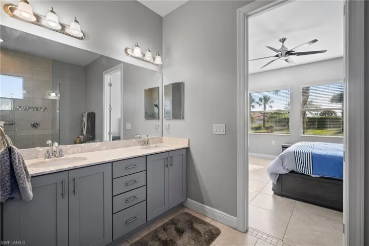 Bathroom with tile patterned floors, ceiling fan, vanity, and tiled shower