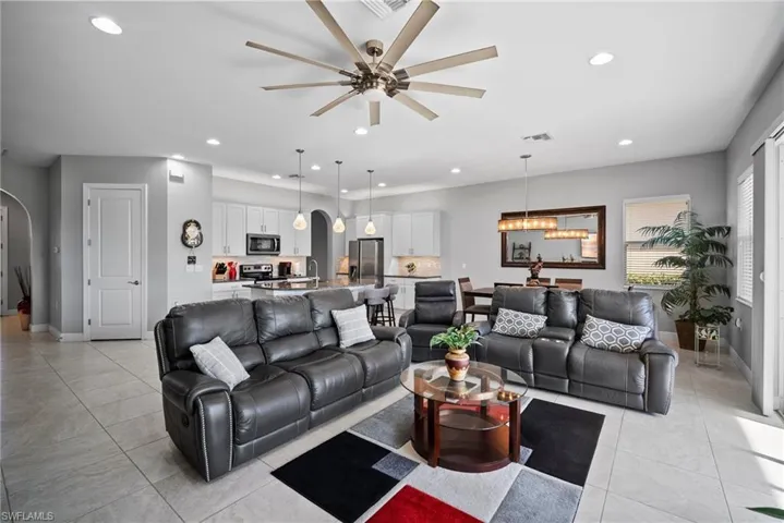 Tiled living room featuring ceiling fan with notable chandelier