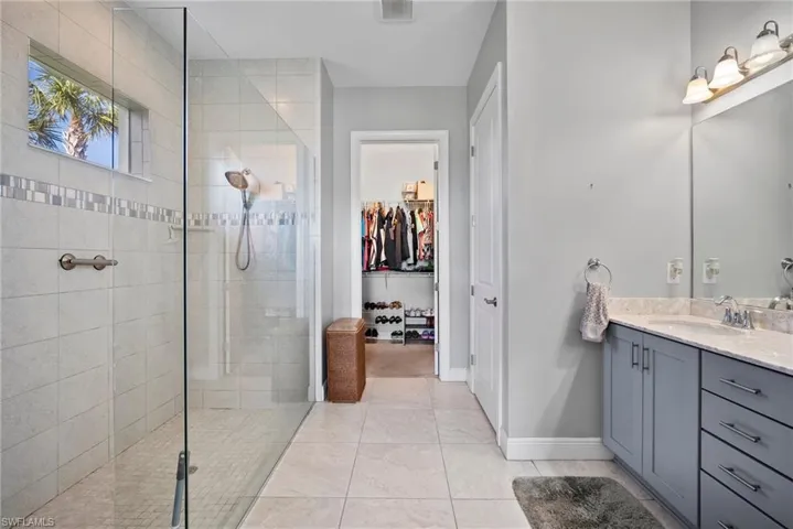 Bathroom featuring a tile shower, tile patterned floors, and vanity