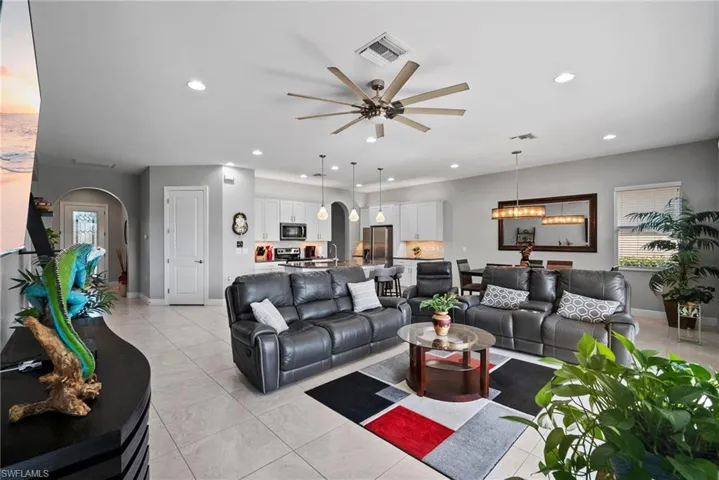 Tiled living room featuring ceiling fan with notable chandelier
