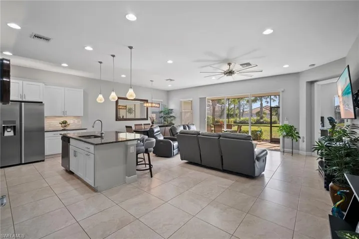 Kitchen with sink, dark stone countertops, a center island with sink, white cabinets, and appliances with stainless steel finishes