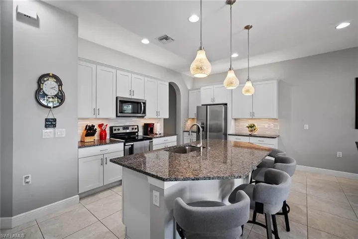 Kitchen featuring an island with sink, white cabinets, and stainless steel appliances