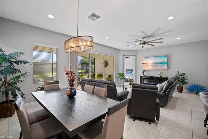 Tiled dining space featuring ceiling fan with notable chandelier