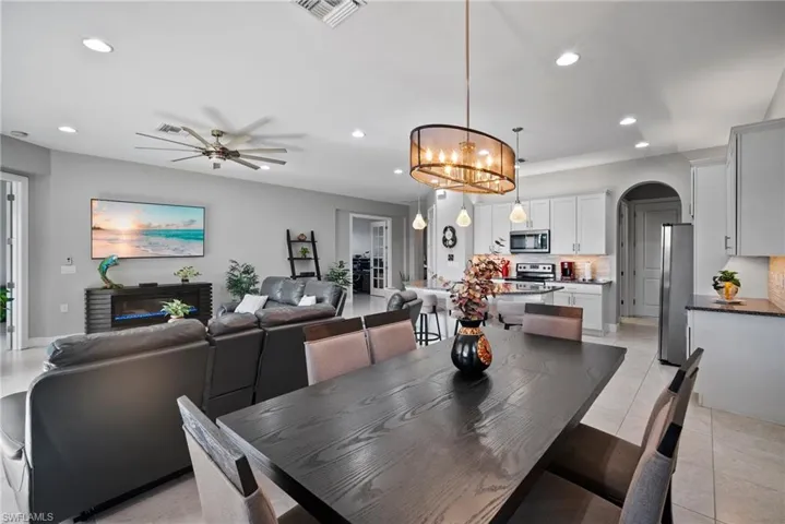 Tiled dining space with ceiling fan with notable chandelier