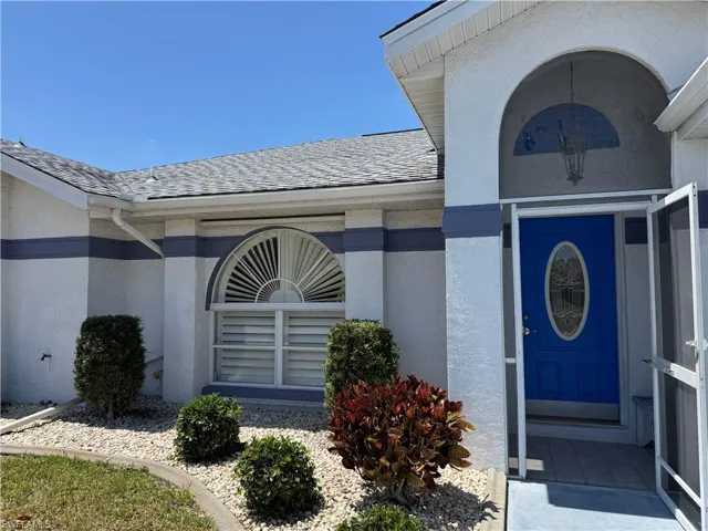 Entrance to property featuring roof with shingles and stucco siding