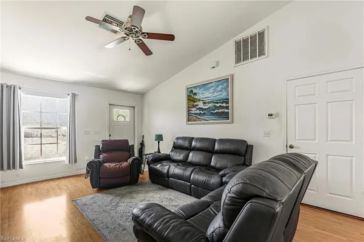 Living room featuring light wood-style flooring, a ceiling fan, and high vaulted ceiling