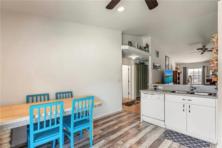 Kitchen with a ceiling fan, white dishwasher, white cabinetry, light wood-type flooring, and lofted ceiling