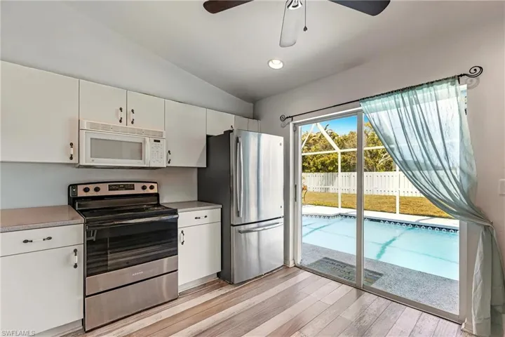Kitchen with stainless steel appliances, white cabinets, light countertops, vaulted ceiling, and recessed lighting