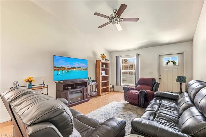 Living area with lofted ceiling, light wood-style floors, and ceiling fan