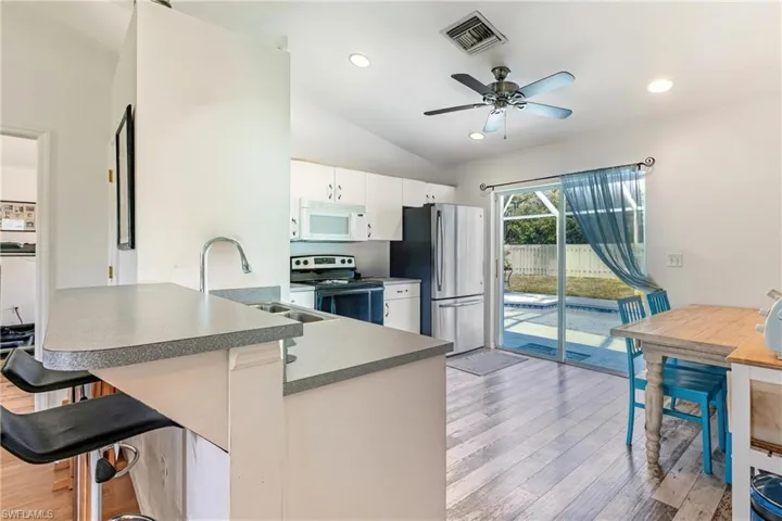 Kitchen featuring a breakfast bar area, a peninsula, stainless steel appliances, vaulted ceiling, and dark countertops
