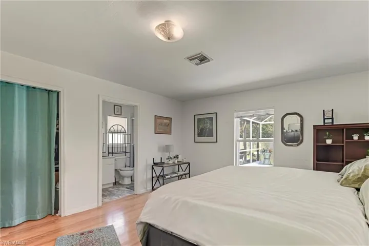 Bedroom featuring multiple windows, light wood finished floors, and connected bathroom
