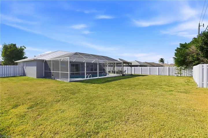 Rear view of property with a fenced backyard, a sunroom, an outdoor pool, and a lanai