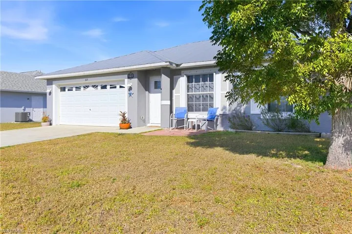 Ranch-style home with driveway, a front yard, stucco siding, a metal roof, and a garage