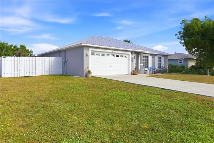 Ranch-style house with driveway, an attached garage, stucco siding, and a metal roof