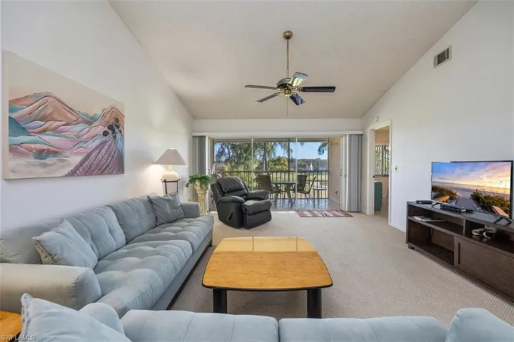 Living area with carpet floors, a ceiling fan, and high vaulted ceiling