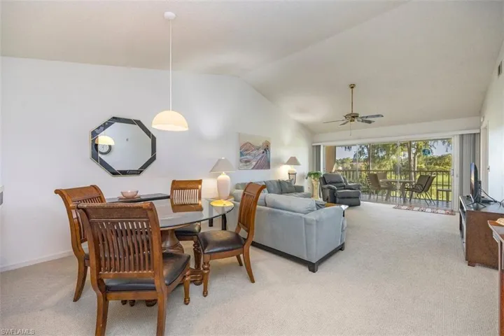 Dining space featuring lofted ceiling, light carpet, and ceiling fan