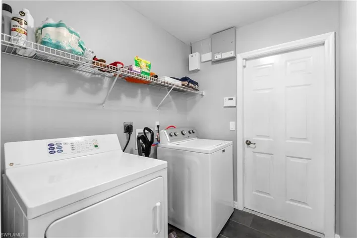 Laundry area featuring dark tile patterned flooring and washer and dryer
