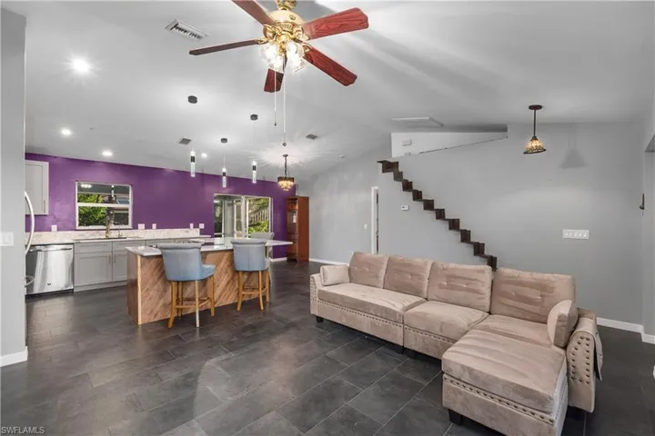 Living room featuring a ceiling fan, vaulted ceiling, stairway, and recessed lighting