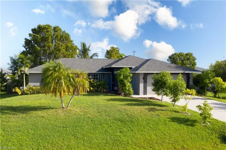 Single story home featuring a front yard, driveway, roof with shingles, stucco siding, and a garage