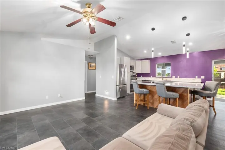 Living room with vaulted ceiling, a ceiling fan, and recessed lighting