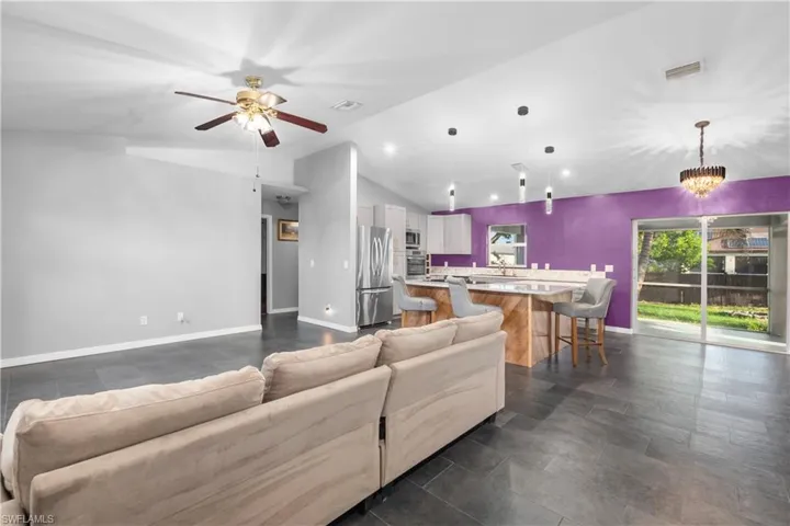Living room with vaulted ceiling, a chandelier, recessed lighting, and ceiling fan