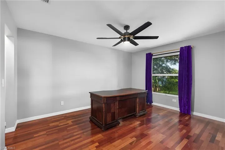 Unfurnished bedroom featuring dark wood flooring and ceiling fan