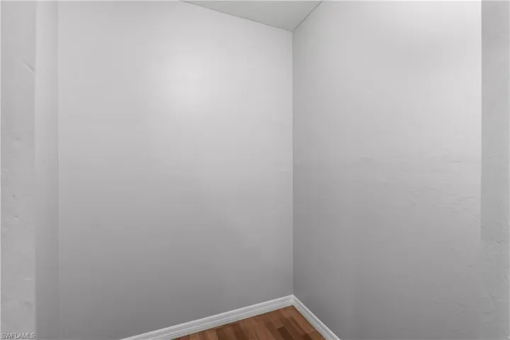 Unfurnished room with dark wood flooring and baseboards