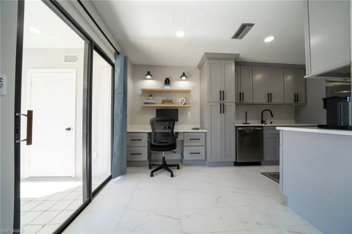 Kitchen with stainless steel dishwasher, sink, and gray cabinetry