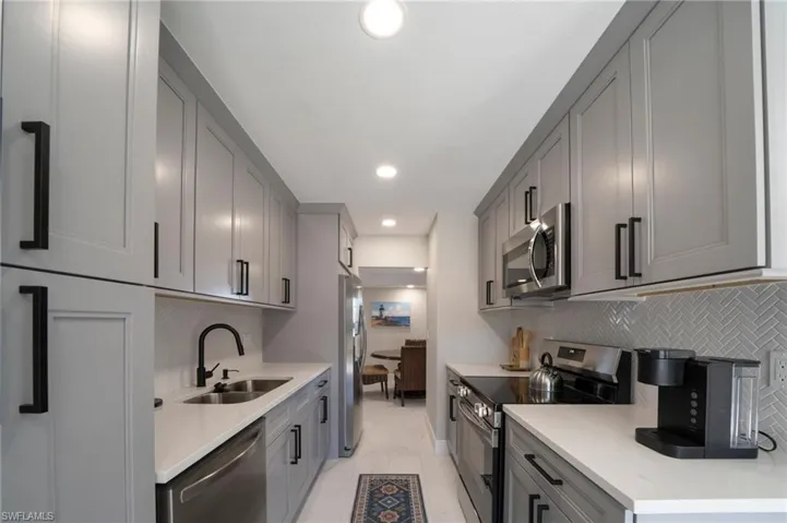 Kitchen with sink, light tile patterned floors, appliances with stainless steel finishes, gray cabinetry, and tasteful backsplash
