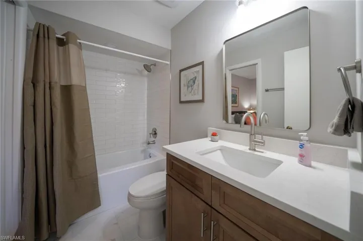Full bathroom with vanity, tile patterned flooring, shower / bath combination with curtain, and toilet