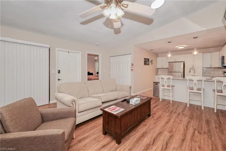 Living room featuring ceiling fan, light hardwood / wood-style flooring, lofted ceiling, and sink
